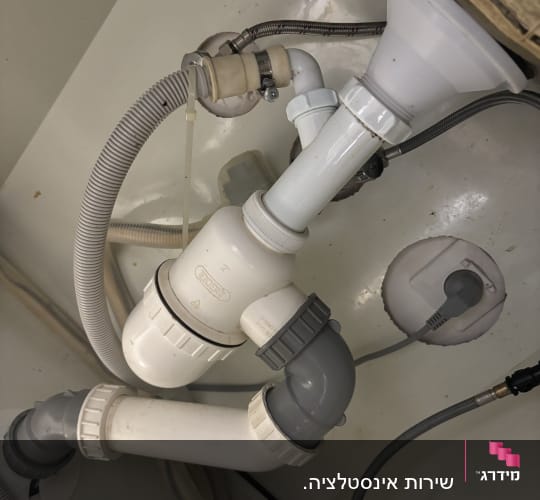צנרת מתחת לכיור עם חיבורים וצינורות